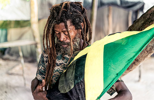 Man with dreads holding Jamaican flag